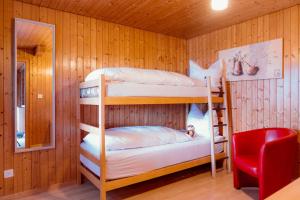 two bunk beds in a room with a red chair at Apartment Bergdohle in Amden