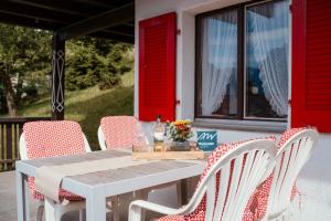 a table and chairs on a porch with red doors at Apartment Bergdohle in Amden