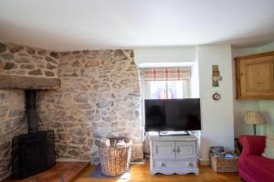 a living room with a stone wall with a flat screen tv at The Forge in Bakewell