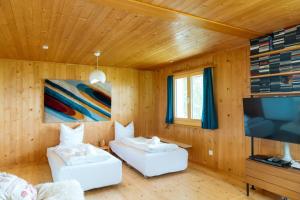 a room with two white couches and a flat screen tv at Chalet Engihalde in Amden