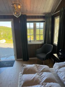 a bedroom with a bed and a chair and a window at Vikerfjell i Ringerike, Oslos nærmeste høyfjell in Hønefoss