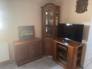 a living room with a tv and a wooden entertainment center at Pension Wolkenheim in Wöbbelin