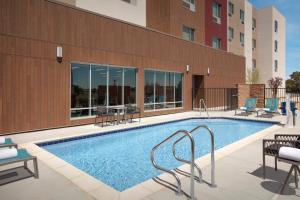 a swimming pool with chairs and a building at TownePlace Suites by Marriott Palmdale in Palmdale