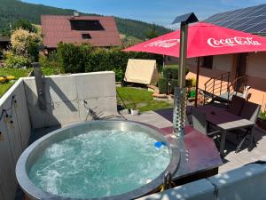 a hot tub on a patio with an umbrella at Penzion Ján in Habovka