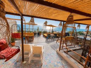 a patio with chairs and tables and a view of the ocean at Miramar Surf Anza in Agadir