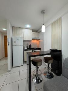 a kitchen with a white refrigerator and a counter with stools at West Flat - BarretoStays 03 in Mossoró