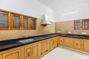 a large kitchen with wooden cabinets and a sink at Fernwood stays in Haidar Sāhibgūda