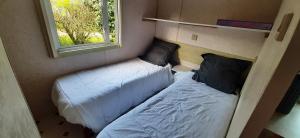 two beds in a small room with a window at Mobil-Home location in Plougrescant