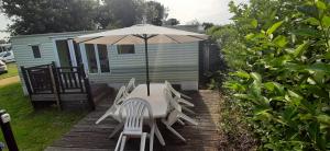 a table and chairs under an umbrella on a deck at Mobil-Home location in Plougrescant