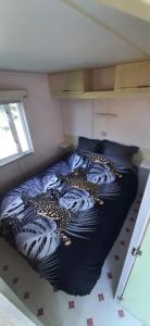 a bedroom with a bed with a black and white comforter at Mobil-Home location in Plougrescant