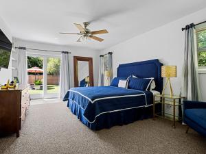 a bedroom with a blue bed and a ceiling fan at Beautiful 6-Bedroom Escape Featuring a Private Pool in Hampton Bays +19 photos