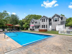 a swimming pool in front of a house at Beautiful 6-Bedroom Escape Featuring a Private Pool in Hampton Bays
