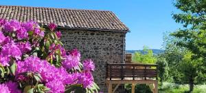 a stone building with purple flowers in front of it at Clos De La Ronziere Avec Jacuzzi in Soulages