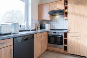 a kitchen with wooden cabinets and a black dishwasher at Haus Roland, Wohnung 19 in Zinnowitz