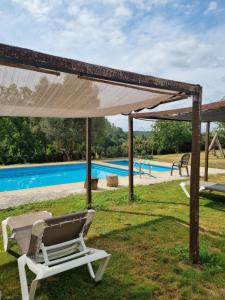 a chair under a canopy next to a swimming pool at Casa Gasamáns in Amés