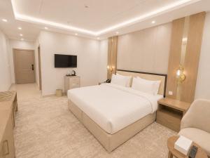 a bedroom with a large white bed and a chair at Jwana in Riyadh