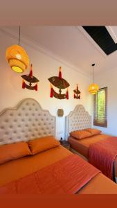 a bedroom with two beds with orange sheets and chandeliers at Bunohan Villa Roomstay in Tumpat +17 photos