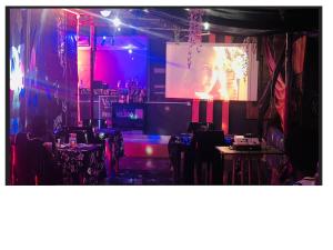 a room with a projection screen in a room with tables at Pandorax Hotel and Lounge in Benin City