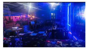 a room with blue lights and people sitting at tables at Pandorax Hotel and Lounge in Benin City