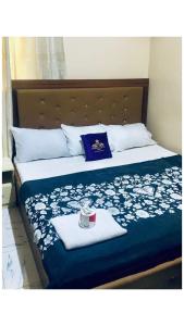 a bed with a blue and white comforter with a candle on it at Pandorax Hotel and Lounge in Benin City
