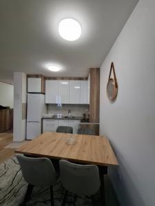a kitchen with a wooden table and chairs at Apartman THE VIEW in Vranješ