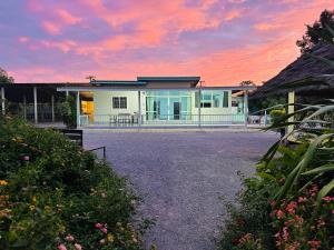 a white house with a sunset in the background at หลัง 1 เฌอเฌอ การ์เด้น เฮาส์ ที่พักคำชะโนด in Ban Nong Sawang