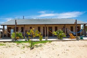 a house on the beach with a hammock in front of it at Loft Rosa - Pousada Vila Dondom in Luis Correia