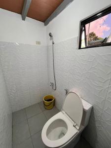 a white bathroom with a toilet and a window at Leonaldo's Farm and Staycation in Kinalaglagan +10 photos