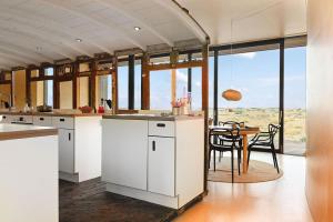 a kitchen with white cabinets and a table and chairs at El Ray by Bloom Stays in Dungeness