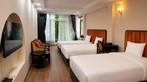 a hotel room with three beds and a television at The 39 Lane Hotel Hanoi in Hanoi +65 photos
