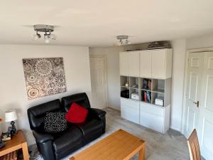 a living room with a black leather couch and a table at Light & Airy flat, Amazing view in Whitefield