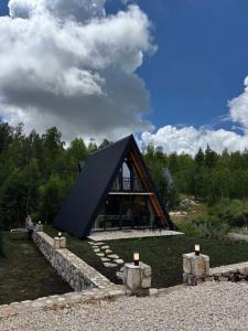 a black triangular house with a stone wall at Frogland in Žabljak