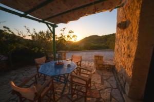 a table and chairs on a patio with the sunset at Revera Traditional Stone Villas, Apartments & Studios in Keri