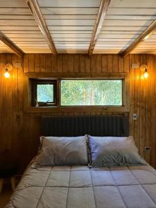 a bed in a wooden room with a window at Cabañas Mountain Fox in Puerto Varas +7 photos