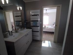 a bathroom with a sink and a mirror and a bed at Chambre Terre et Mer-Millet in Gréville-Hague