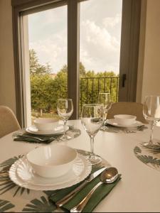 a table with plates and wine glasses and a window at Escolapios Centro in Monforte de Lemos