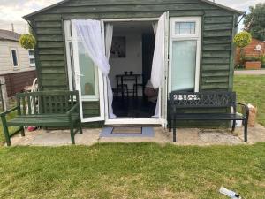 two benches sitting outside of a green shed at The View in Leysdown-on-Sea