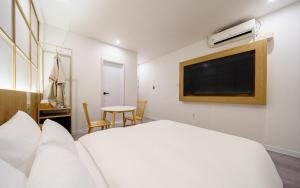 a hotel room with a bed and a flat screen tv at Ryokan Hotel The Red Dragonfly in Incheon +5 photos