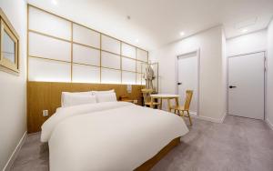 a bedroom with a large white bed and a table at Ryokan Hotel The Red Dragonfly in Incheon