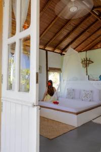 a woman is sitting on a bed in a room at Eco-Casa Bobô in Ilha de Boipeba
