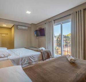 a hotel room with two beds and a large window at Villa di Cavi Hotel in Gramado