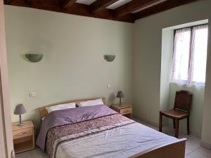 a bedroom with a bed and a chair and a window at Douceur Meyralaise in Meyrals