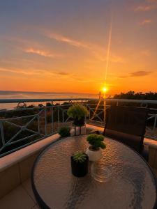 a table on a balcony with a sunset in the background at Velmare apartments in Paralia Vrachou