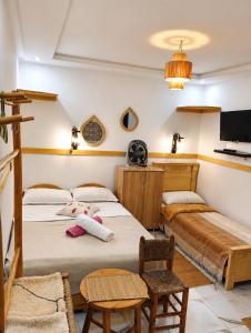 a bedroom with two beds and a flat screen tv at Miramar Surf Anza in Agadir
