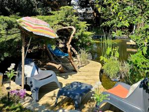 a patio with chairs and an umbrella and a pond at Chambre d'hôtes Le Havre in Saint-Coulomb +10 photos