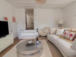 a living room with a couch and a bottle of wine at The Studio Cottage in Denbigh