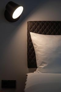 a bedroom with a bed with a white pillow and a lamp at gambino hotel GOETHE26 in Munich