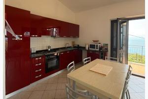 a kitchen with red cabinets and a table with chairs at Panoramic Sea view Deluxe Apartment in Joppolo in Ioppolo