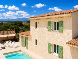 a villa with a swimming pool and green shutters at villa plaisirs in Saint Paul de Vence