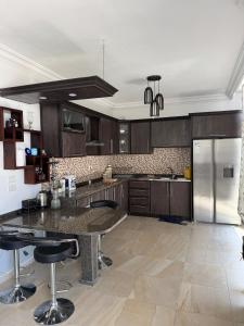 a kitchen with wooden cabinets and a large island with bar stools at Luxury Farm Villa with Private Pool in Jerash